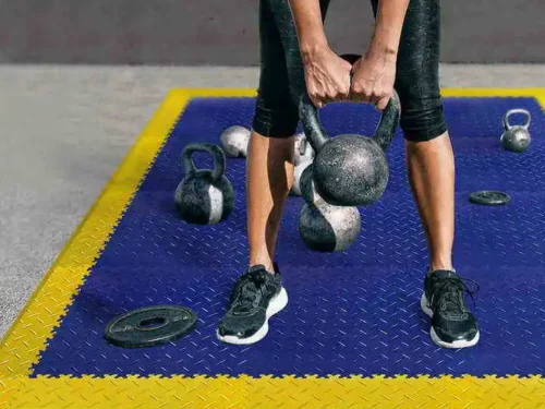 Sportski Podovi Forte za fitnes centre i teretane, u kombinaciji plave i zute sa tegovima na njoj