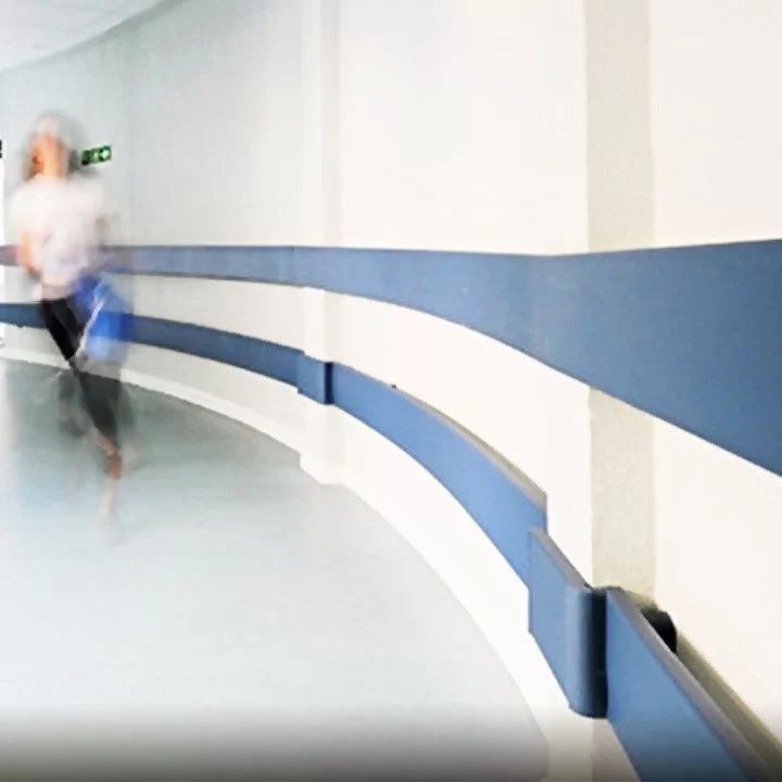 Zidni rukohvati — plavi modularni profili odbojnika montiranog duž zaobljenog bolničkog hodnika