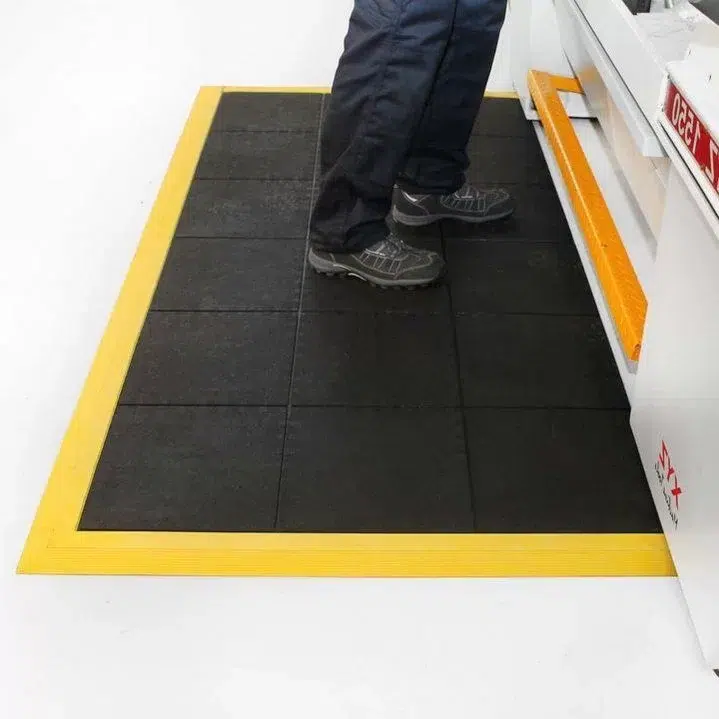 Radnik u pogonu koristi industrijski otirači Fatigu radi smanjenja opterećenja na kičmu i zglobove.