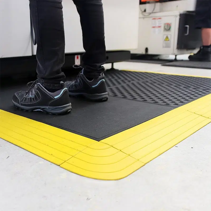 Industrijski otirači Lock postavljeni ispred mašine u proizvodnji – kombinovana instalacija sa žutim ivicama