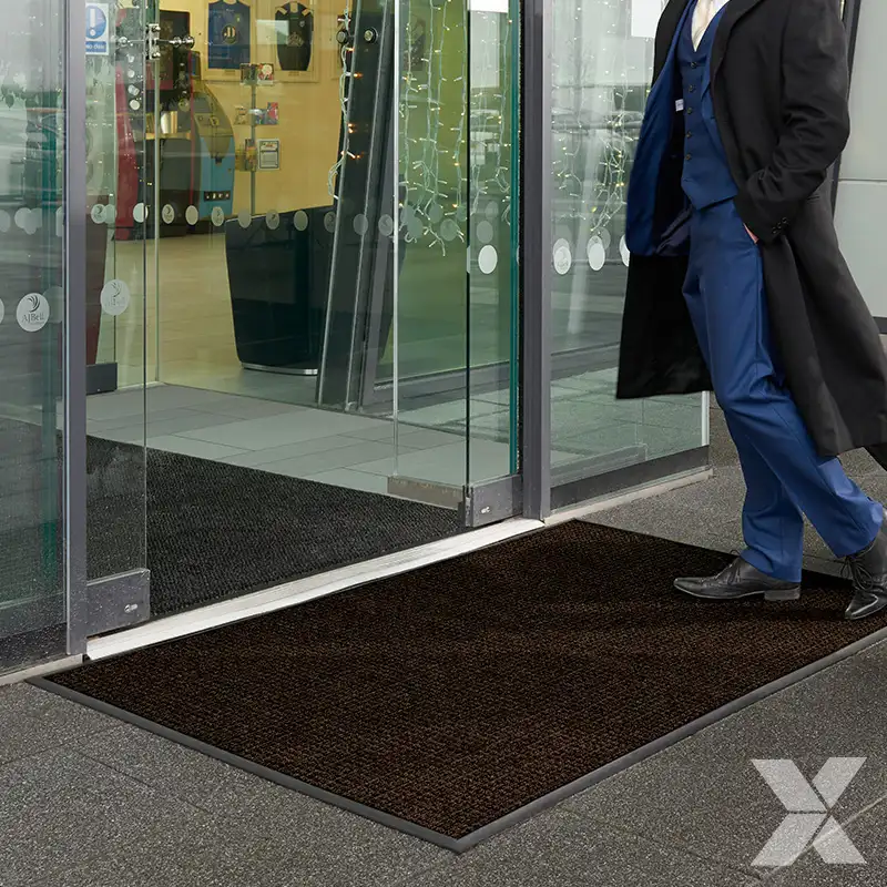 Plus otirači za spoljašnju upotrebu postavljeni ispred staklenih vrata komercijalnog objekta.