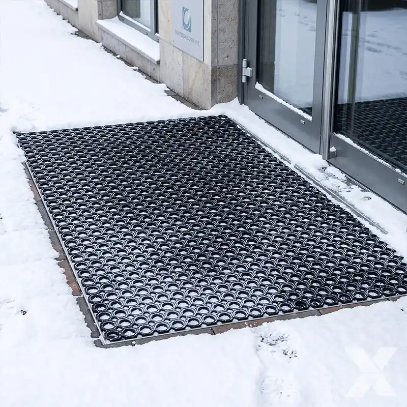 Gumeni otirači za sneg ski pass postavljeni ispred zavejanih ulaznih vrata