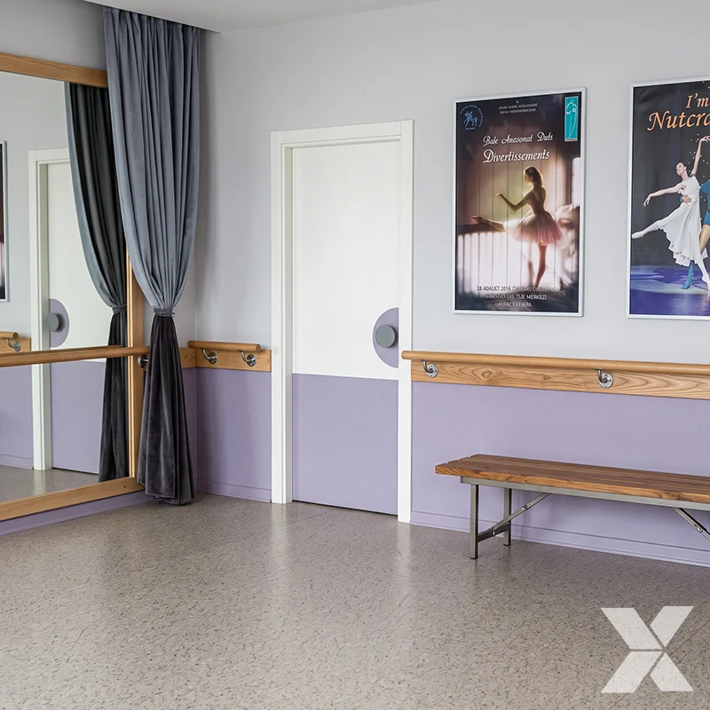 Drveni zidni rukohvati sa inox nosačima postavljeni uz zid u prostoru baletske škole